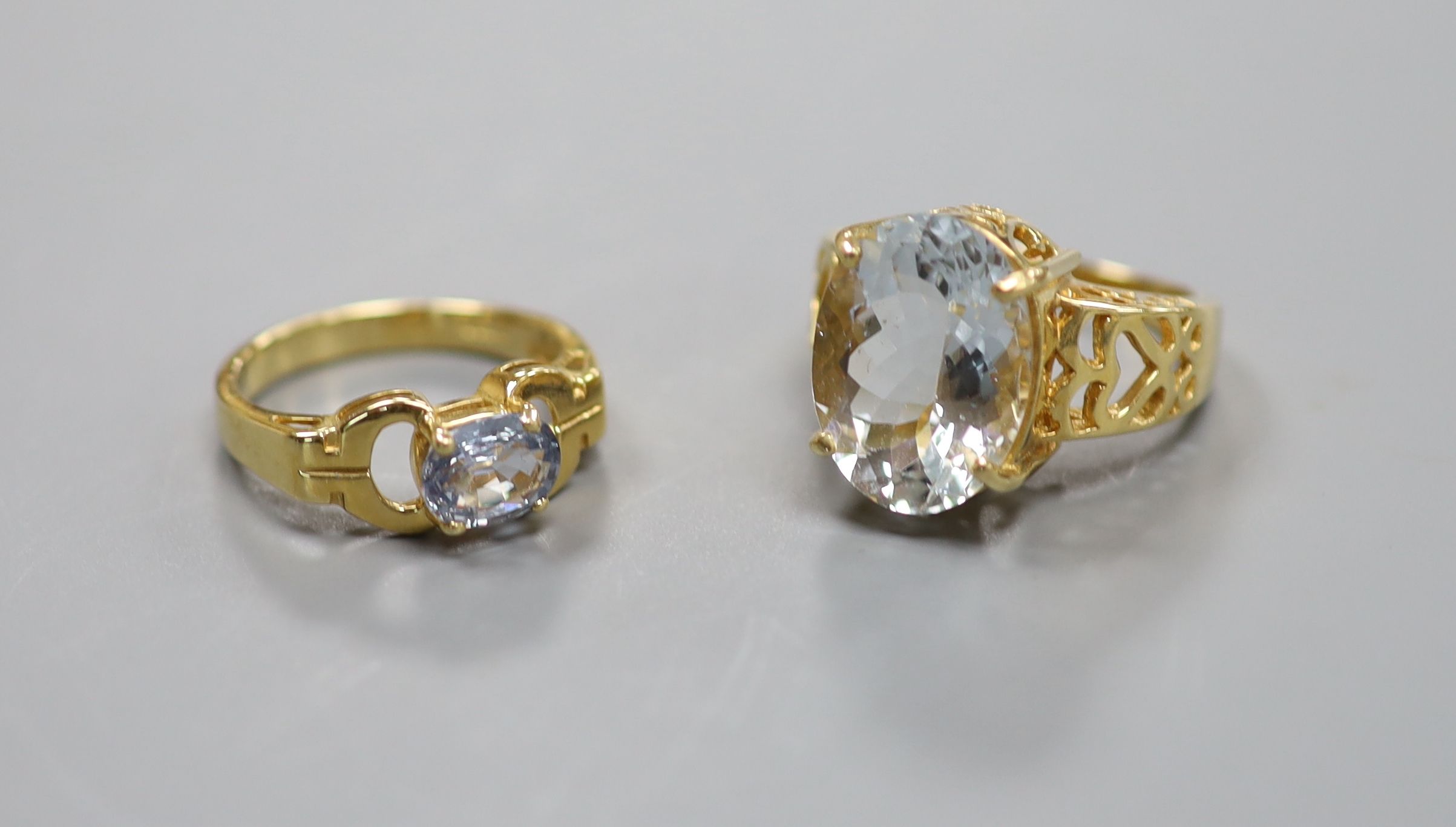 A pale aquamarine ring, pierced 18ct gold setting and shank and an 18ct gold and pale sapphire ring